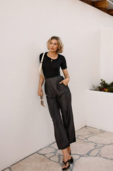 a lady in a black slim top and a pair of grey pants